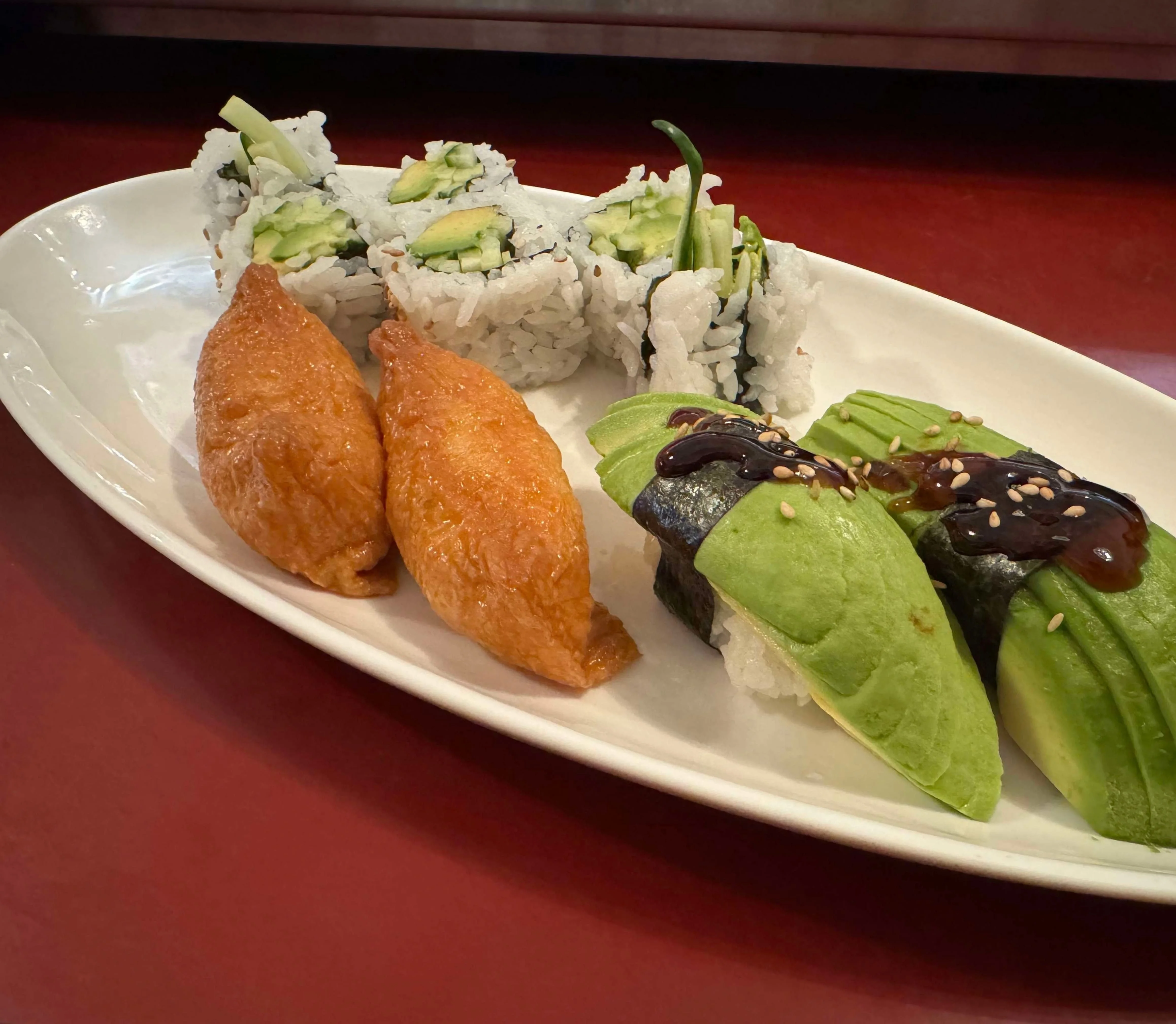 Japanese sushi platter featuring avocado nigiri and cucumber rolls