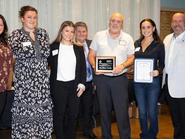 A group of people standing together at an event, some holding awards and certificates.