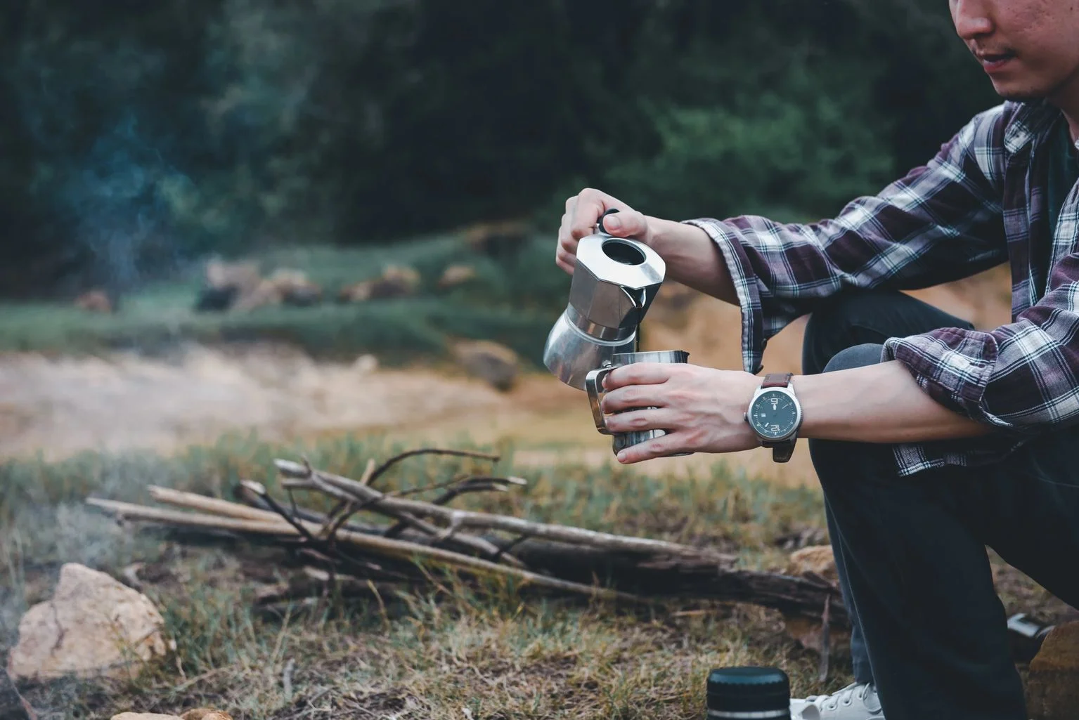 Person brewing coffee outdoors with a moka pot