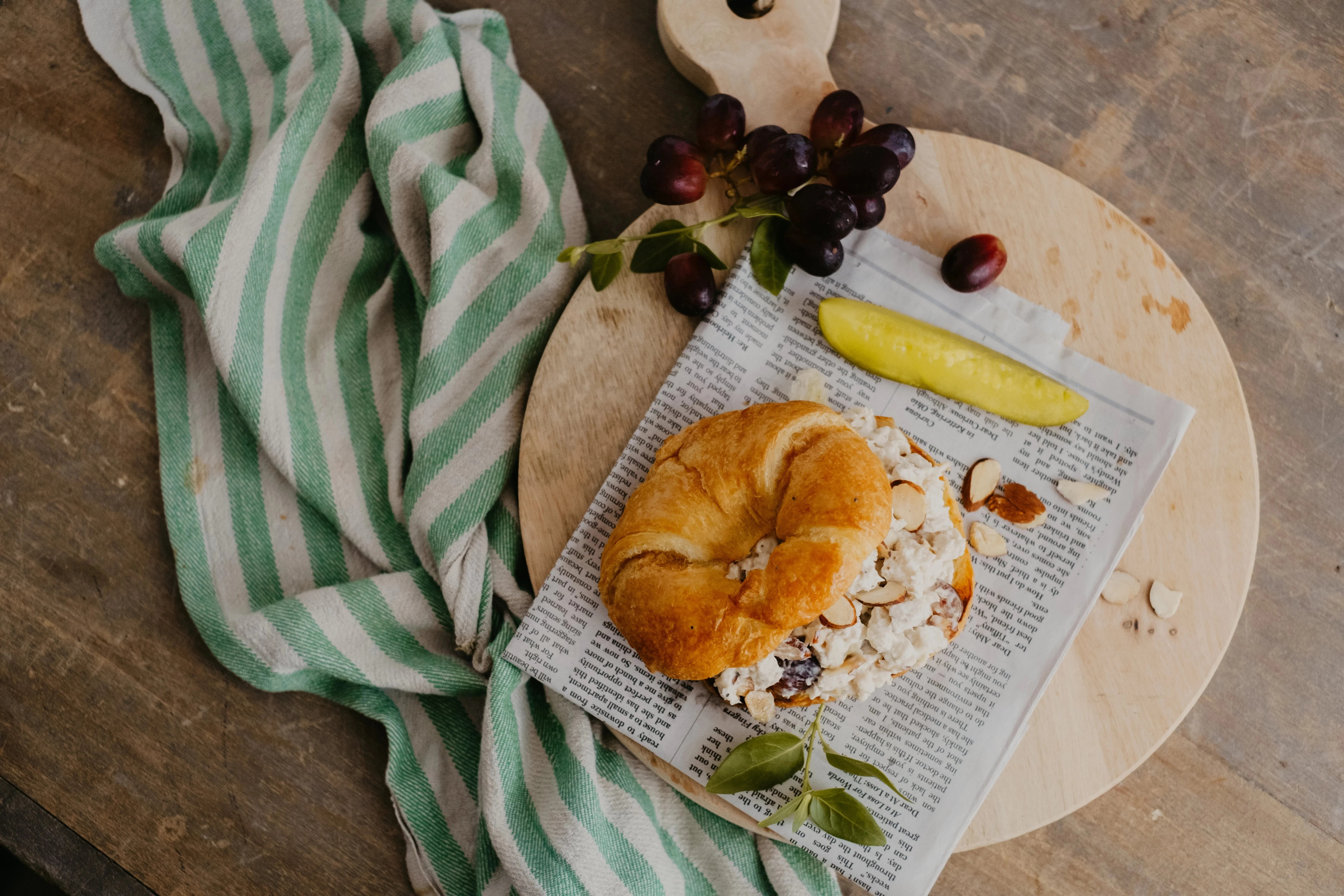 Croissant sandwich with chicken salad, grapes, and pickles