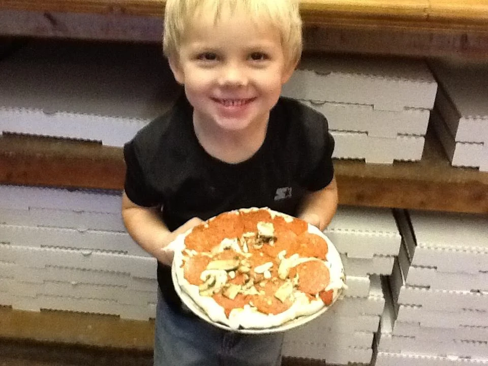 Child holding a homemade pepperoni pizza