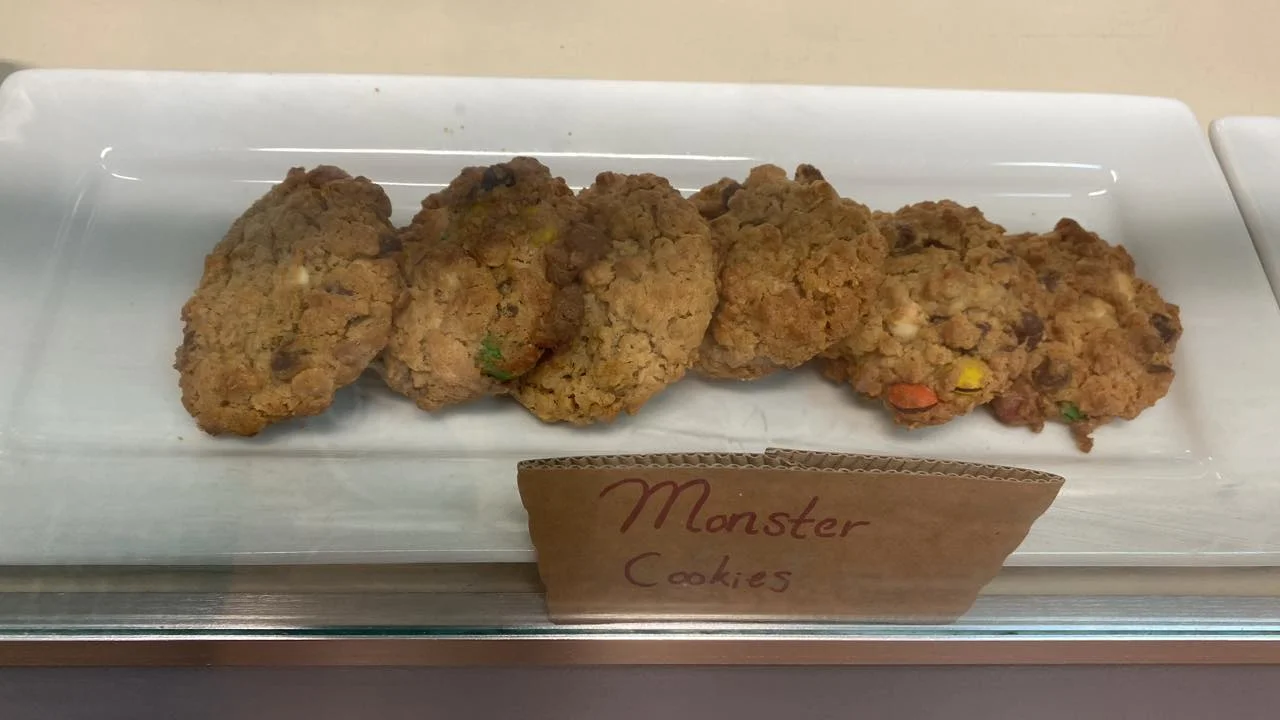 A display of monster cookies placed on a white platter. The cookies have a variety of colorful ingredients visible, giving them a unique look.