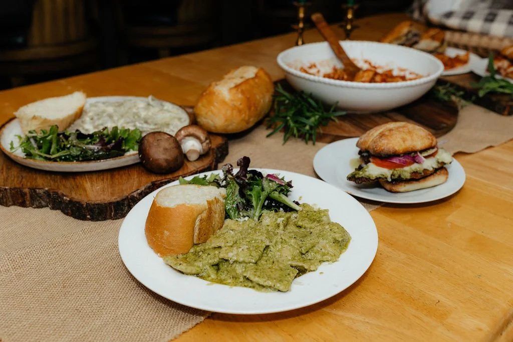 A table with various dishes including pasta, bread, and a sandwich.