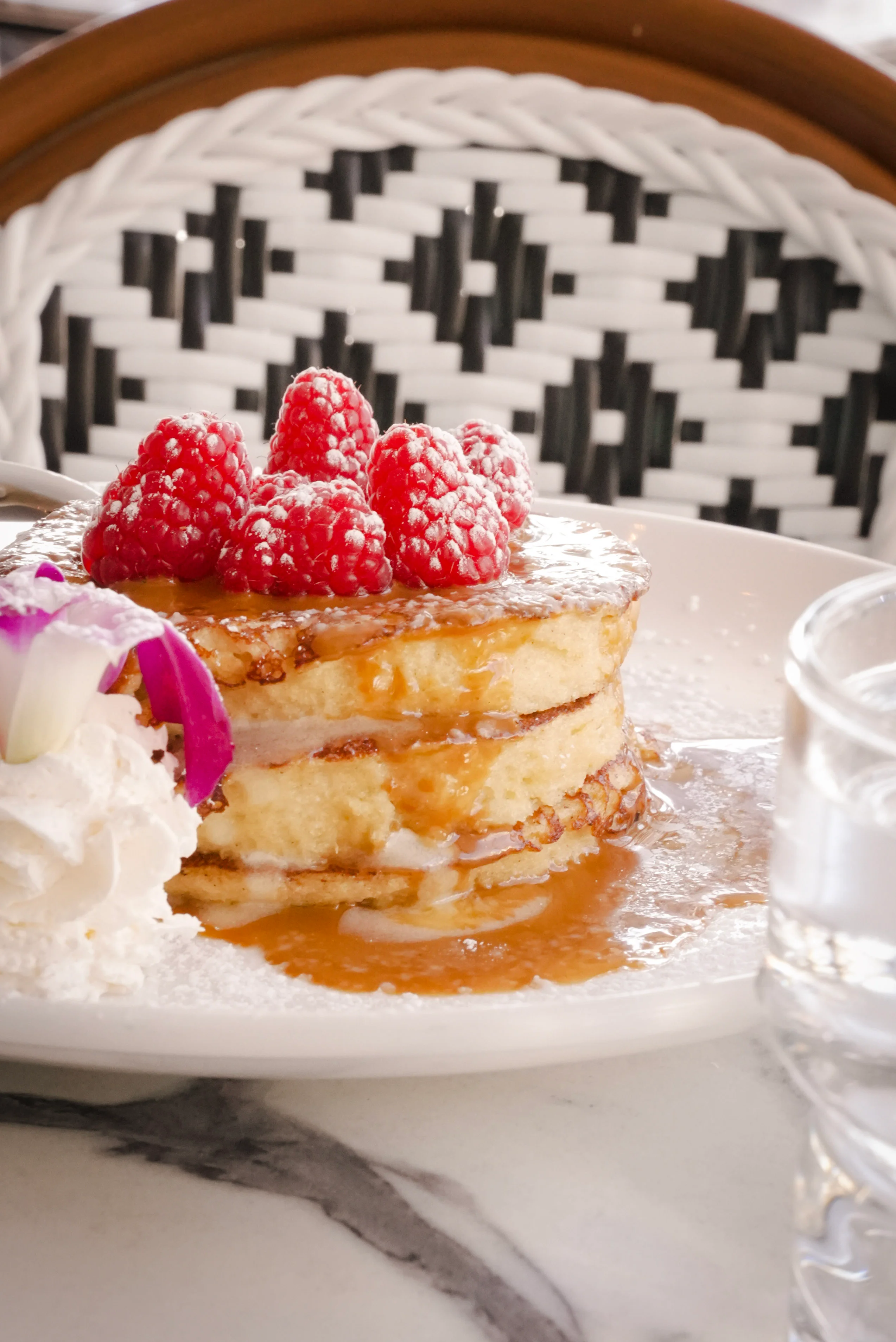 Fluffy pancakes topped with raspberries and syrup