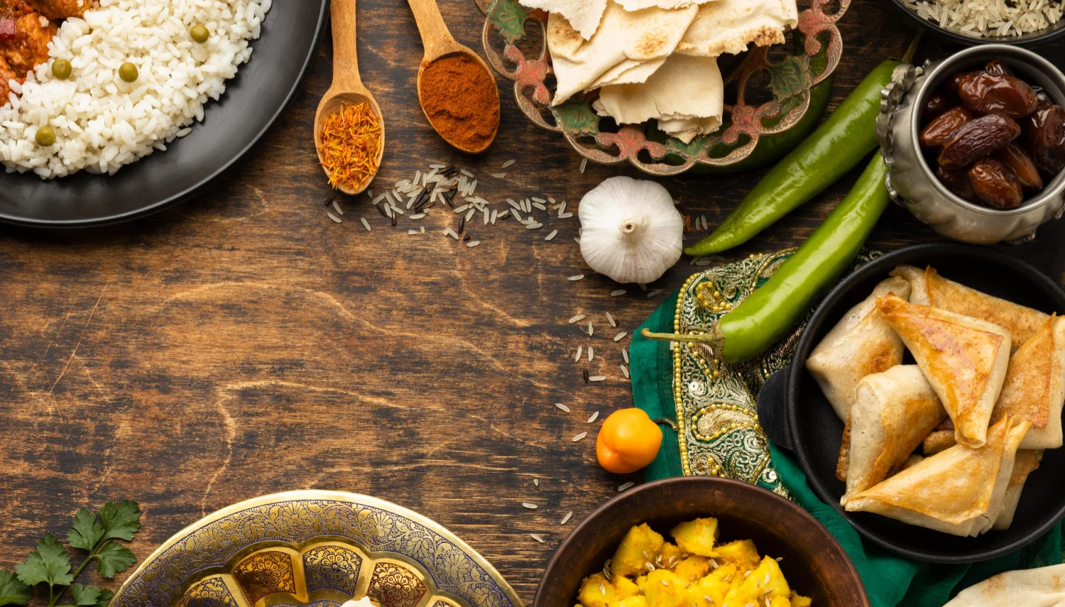 A spread of traditional dishes including rice, bread, and various sides on a wooden table.