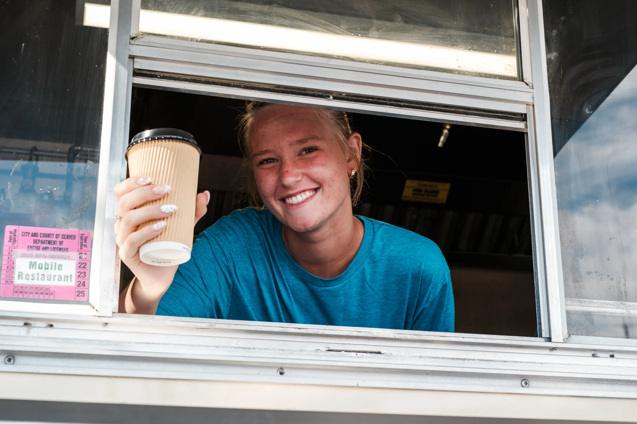Smiling barista serving coffee from a food truck window