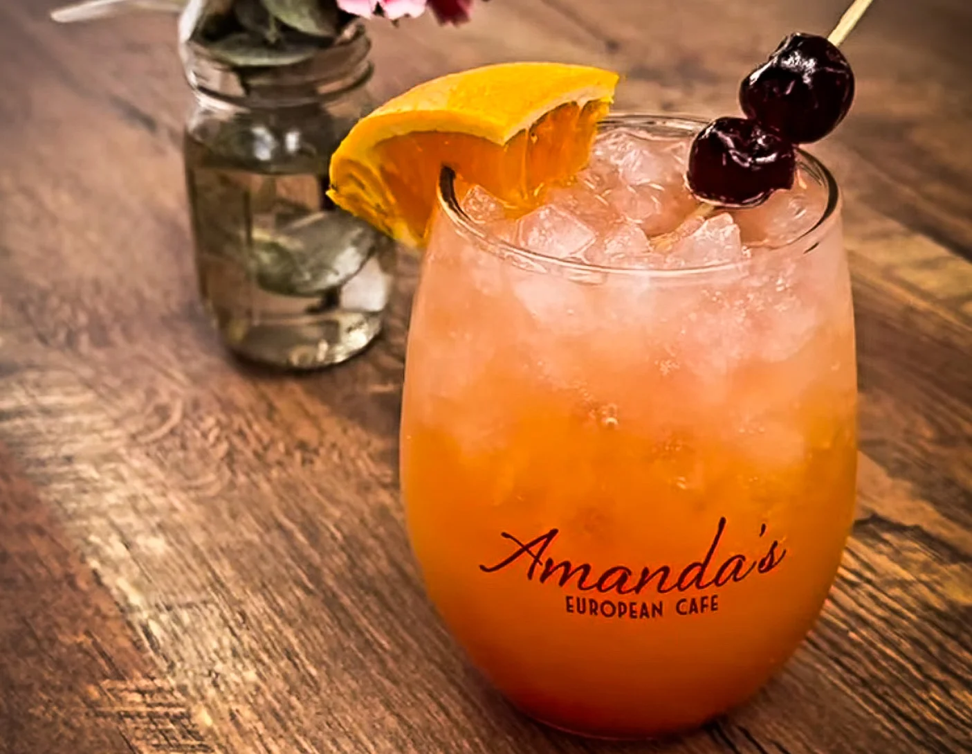 Colorful cocktail with orange slice and cherries at a cafe table