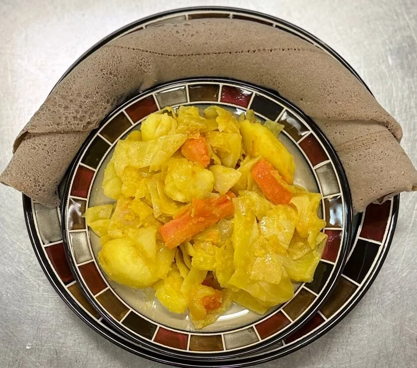 A colorful plate of sautéed vegetables including cabbage, carrots, and potatoes, served with a traditional flatbread.