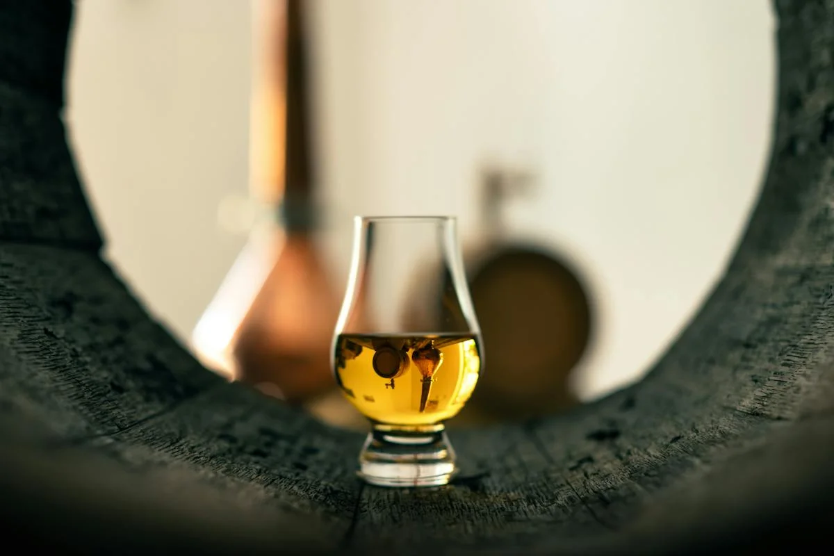 Glowing whiskey tasting glass on a rustic oak barrel
