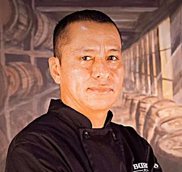 Smiling man in a restaurant with barrels in the background