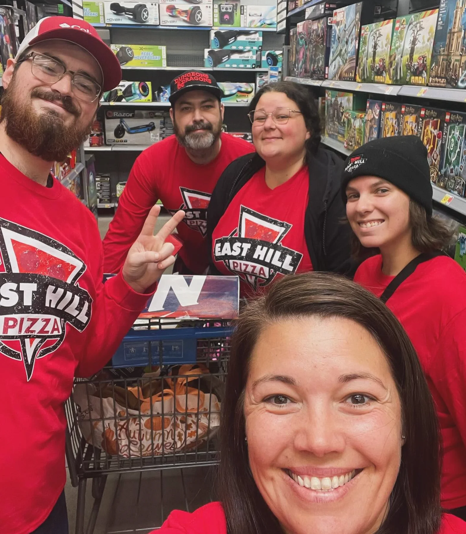 Smiling pizza restaurant team posing in a game and hobby store