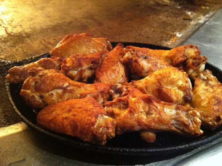 Crispy fried chicken wings served on a sizzling platter
