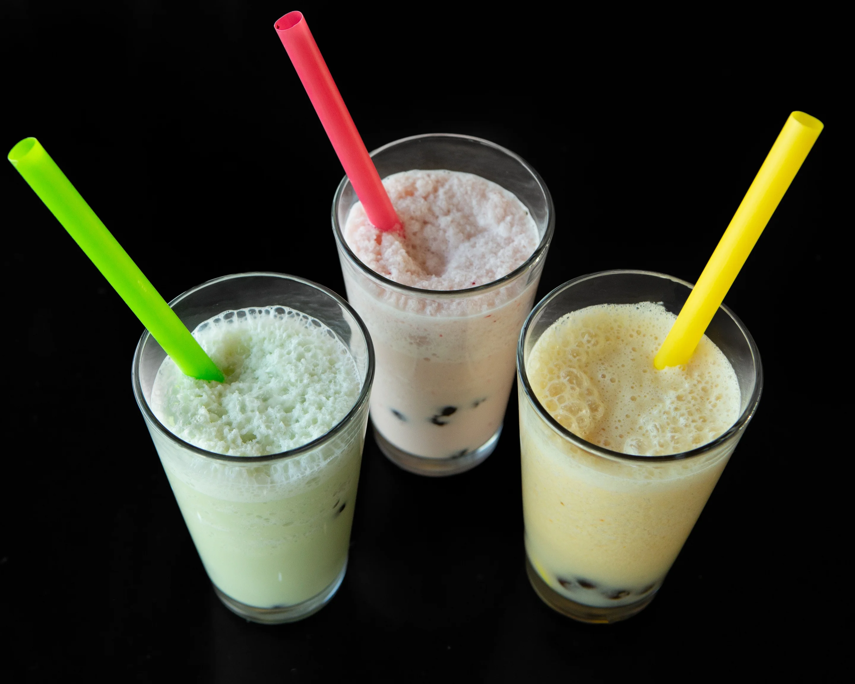 Colorful fruit smoothies in glasses with straws