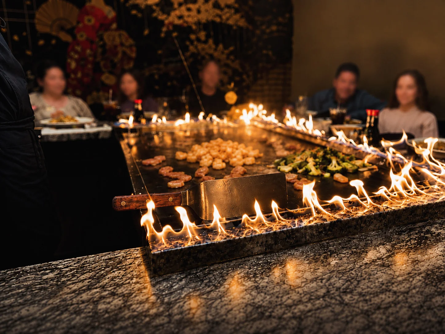 Flaming grill with shrimp and vegetables at a teppanyaki restaurant.