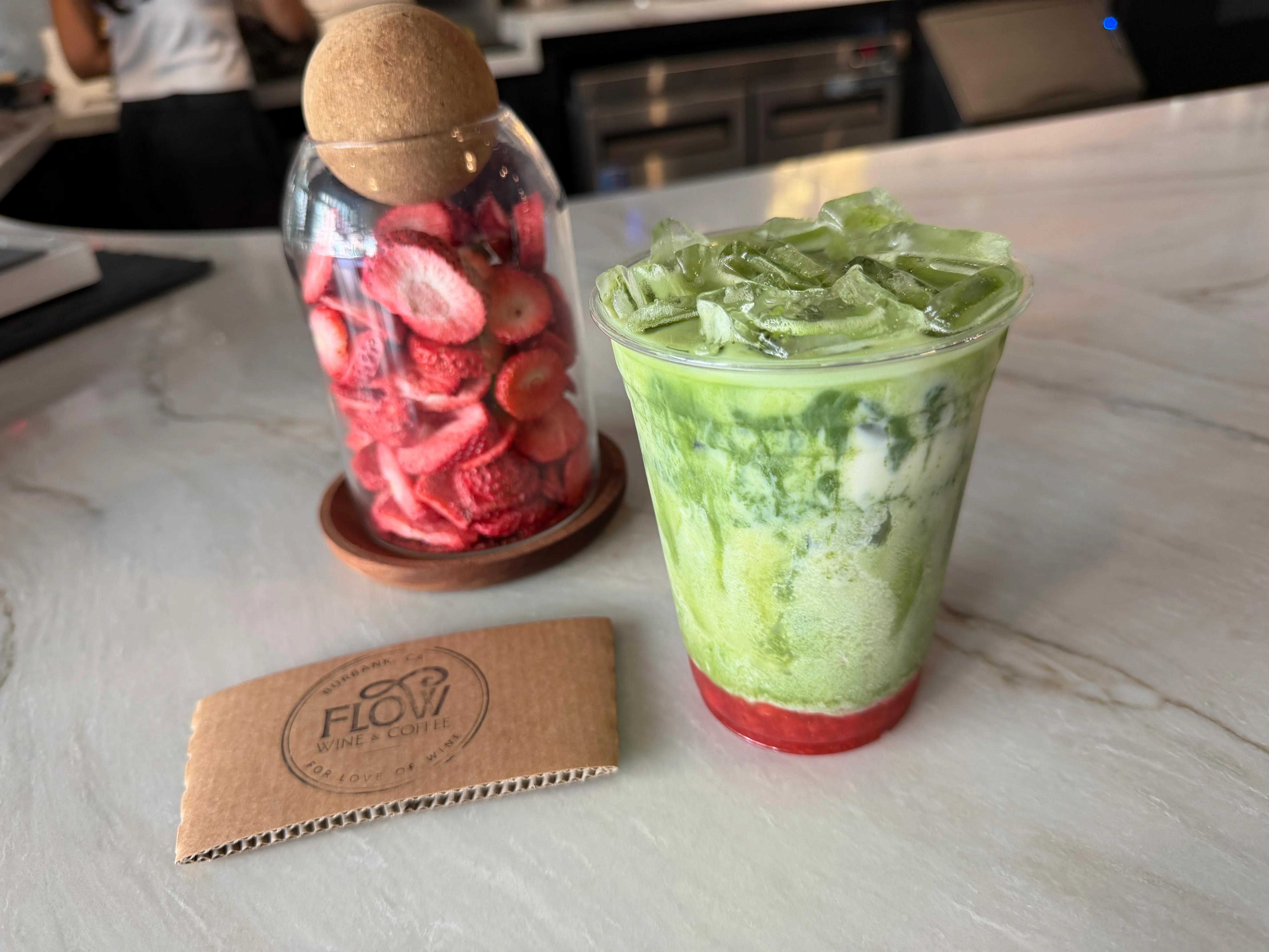 Iced green drink with layered strawberry and matcha in a clear cup.