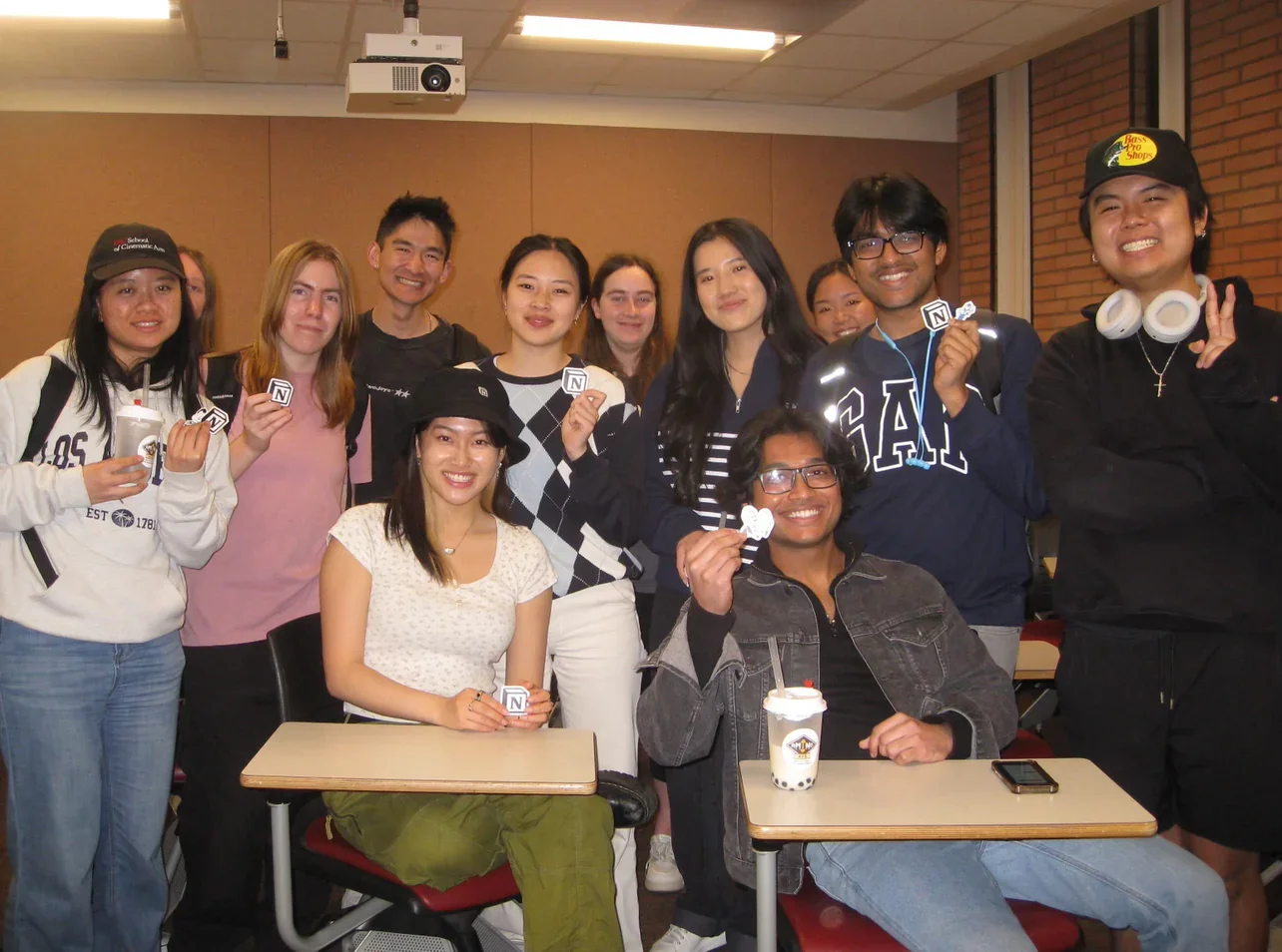 Group of students smiling in a classroom holding stickers