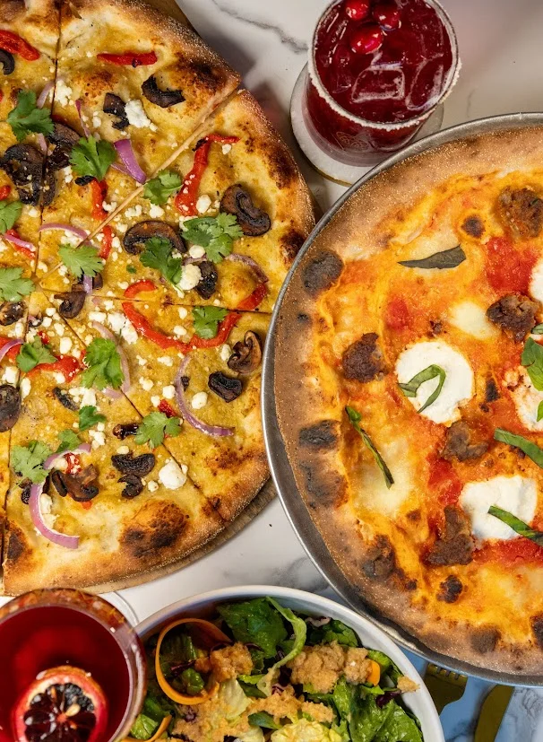 Artisan pizzas with vibrant toppings and a fresh salad