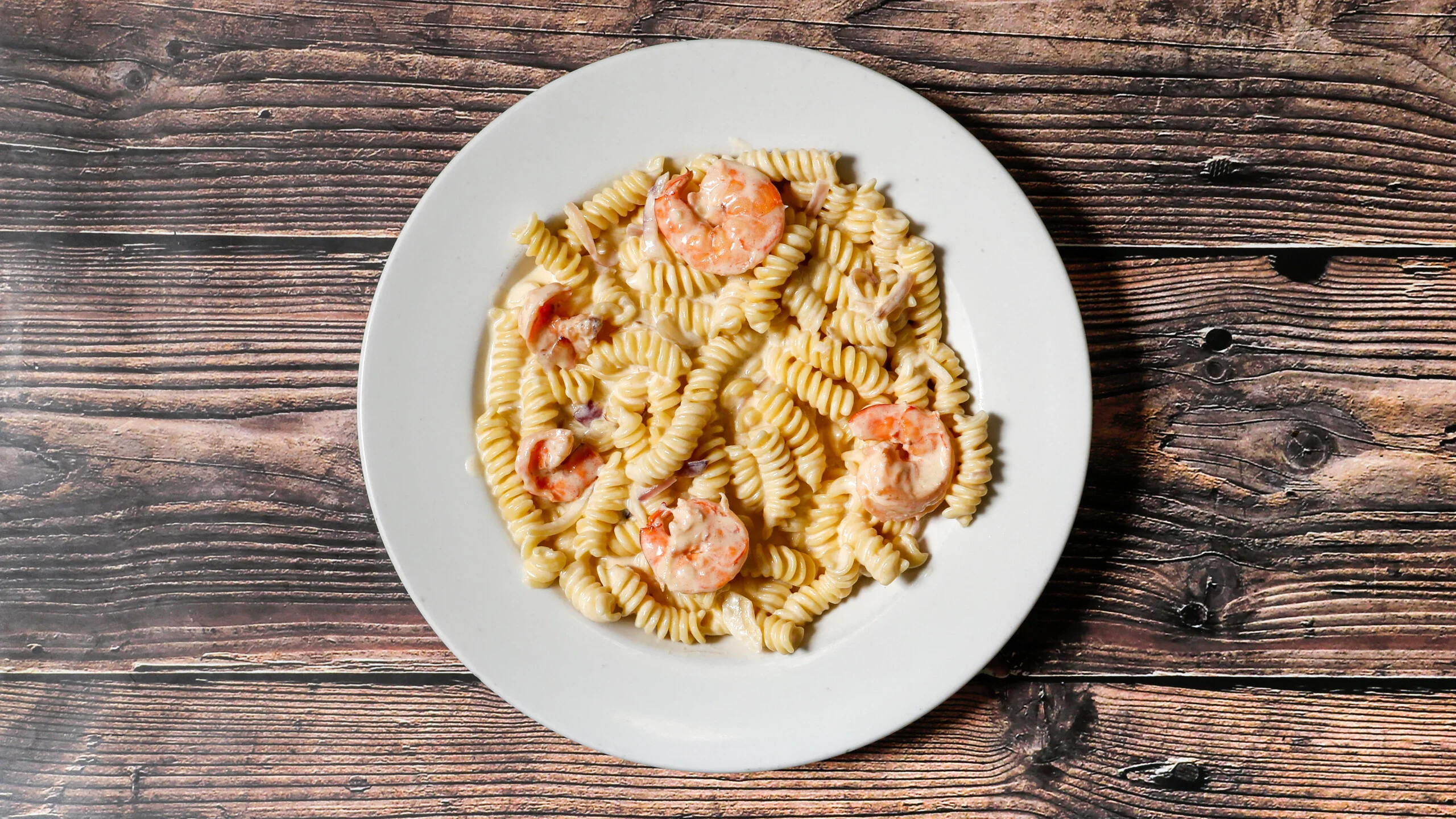 Creamy Italian fusilli pasta with shrimp in a cozy restaurant setting