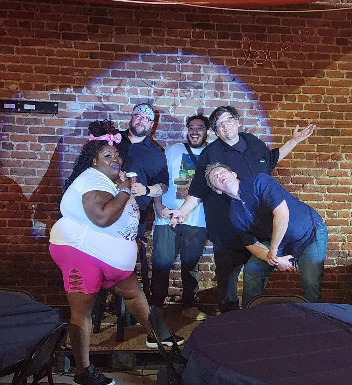 Group of performers posing on stage with a brick wall backdrop