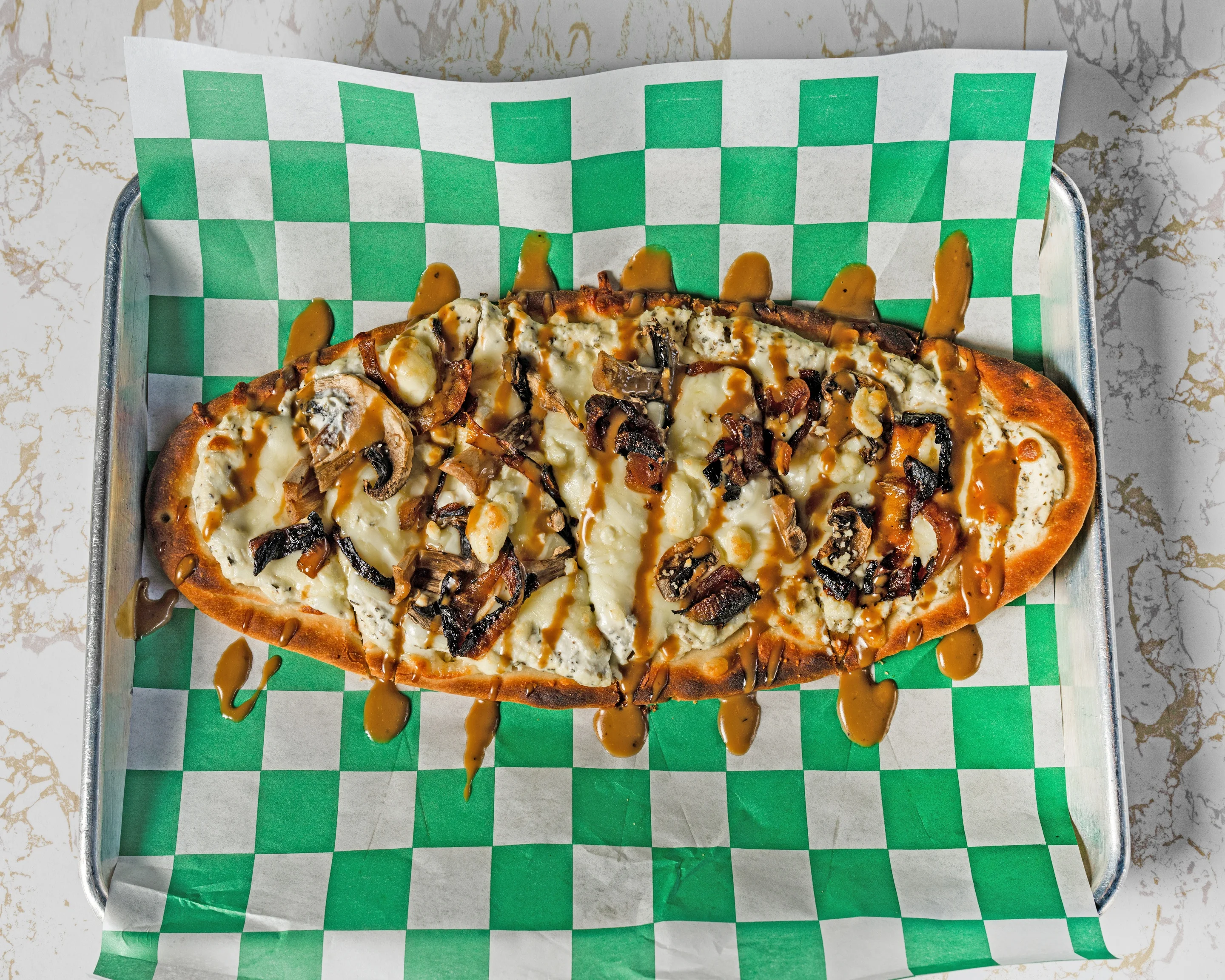 Savory flatbread with mushrooms and cheese drizzled with sauce