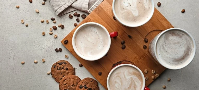 Assorted coffee drinks with cookies on a wooden board