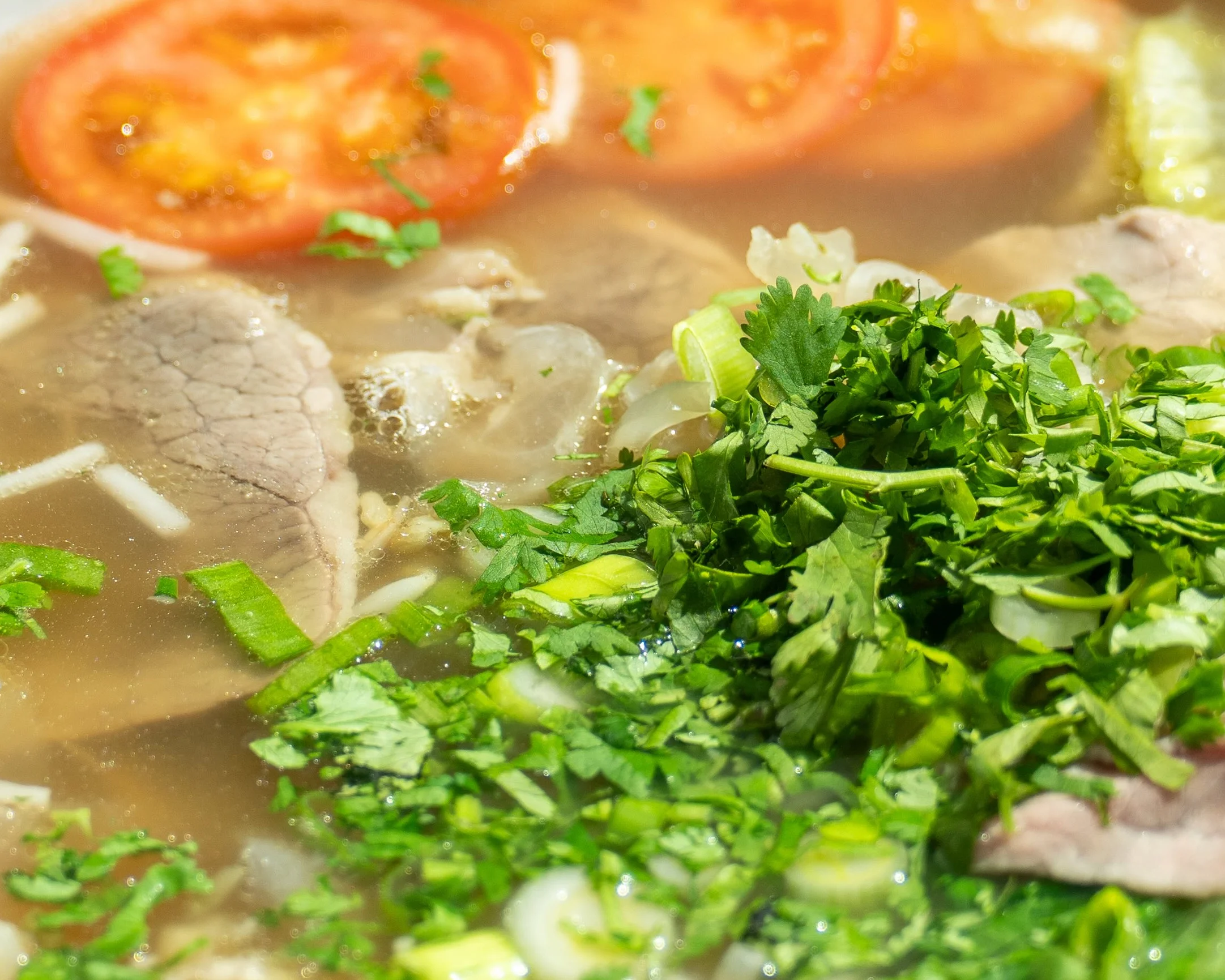 Bowl of Vietnamese pho with fresh herbs and lime