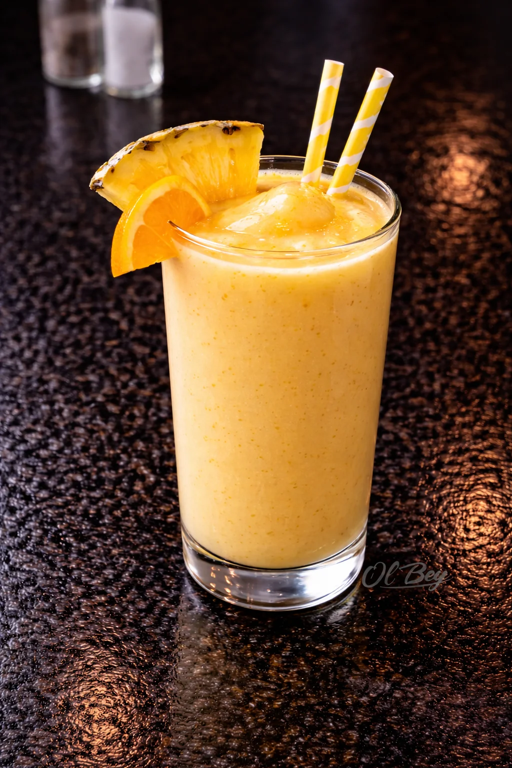 A refreshing smoothie in a clear glass, topped with pineapple and orange slices, and served with two striped straws.