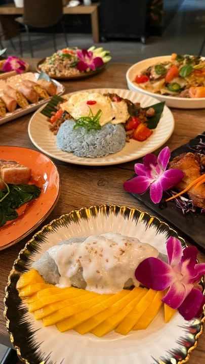 Colorful Thai dishes including mango sticky rice and blue rice with vegetables