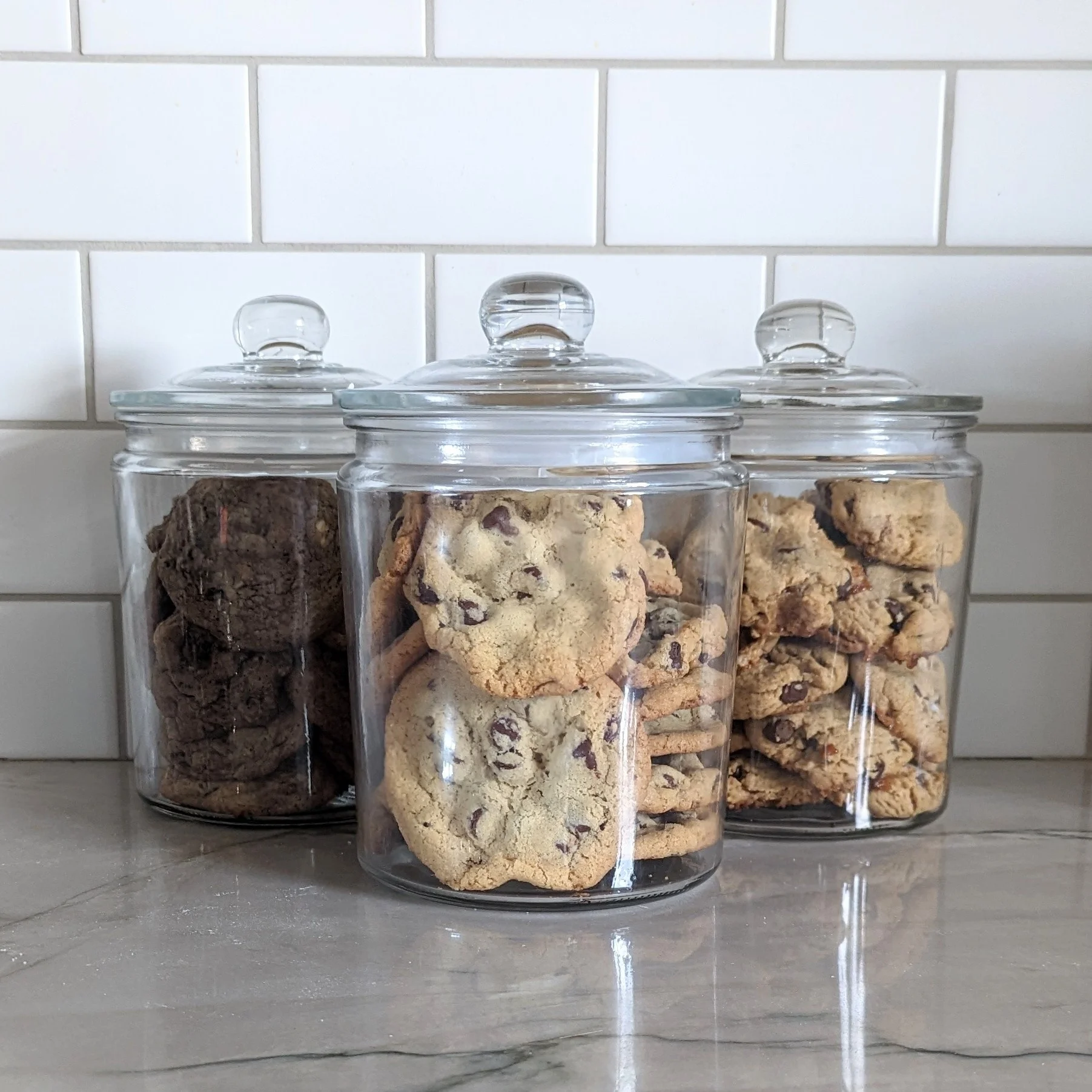 Assorted cookies in glass jars on a kitchen counter