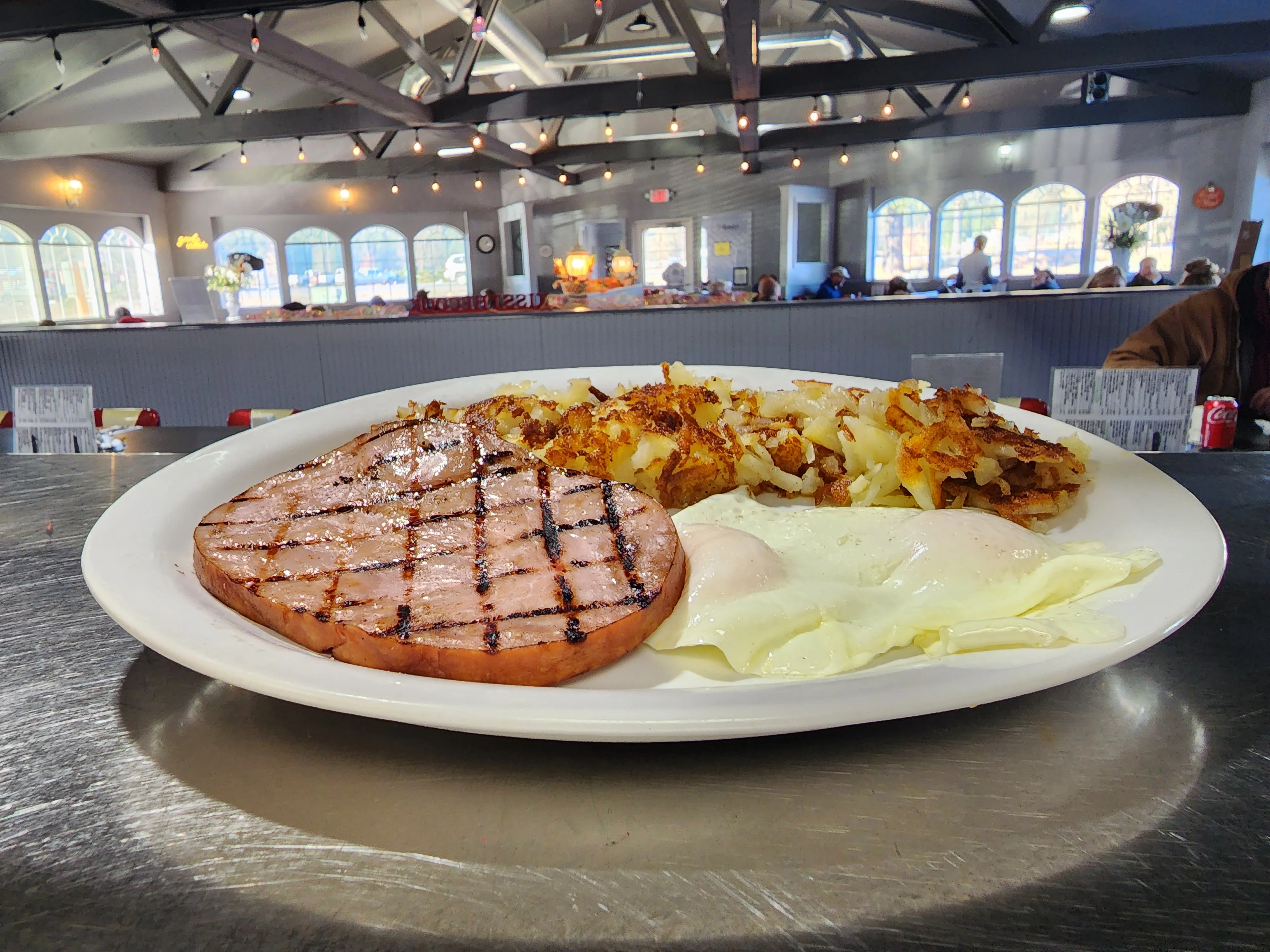 A breakfast plate featuring grilled ham, crispy hash browns, and two poached eggs served on a white plate.