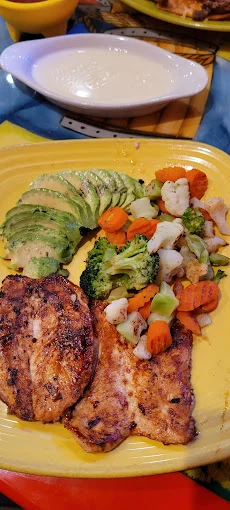 Grilled chicken with avocado and mixed vegetables on a vibrant plate