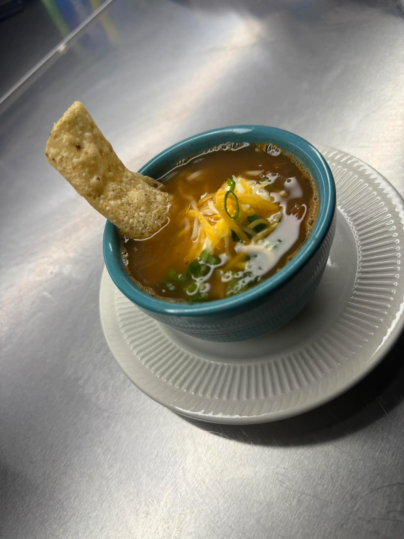 Bowl of Mexican tortilla soup garnished with cheese and green onions