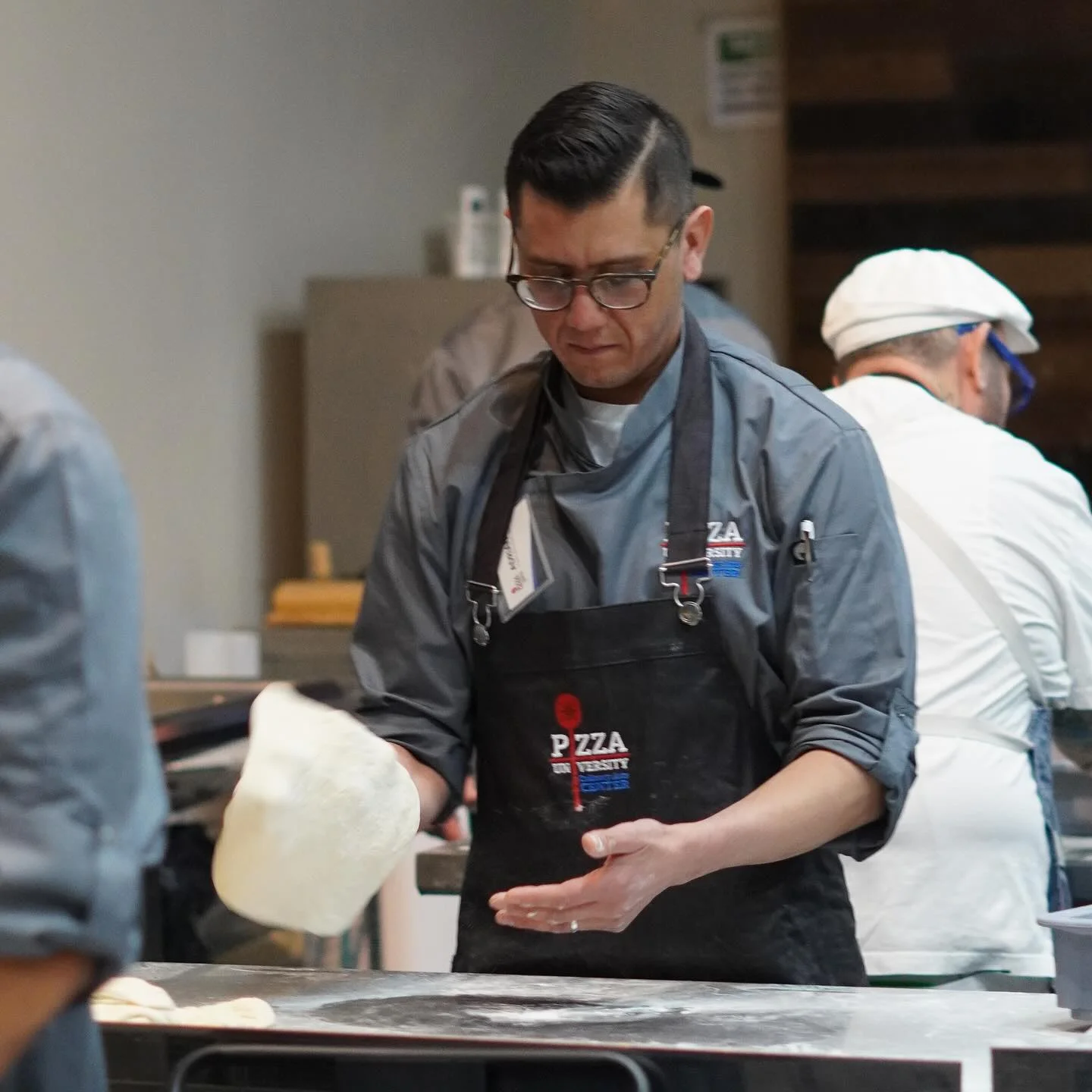 Chef tossing pizza dough at a culinary school