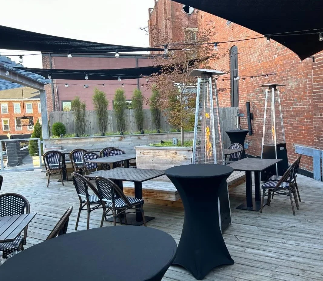 Outdoor terrace event setup with tables and chairs arranged for a gathering.