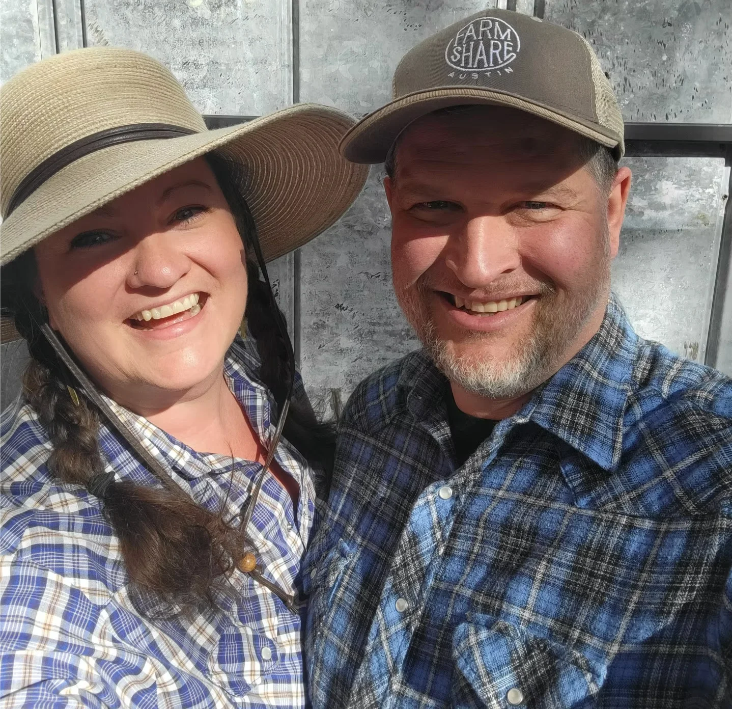 Smiling couple in plaid shirts and hats outdoors