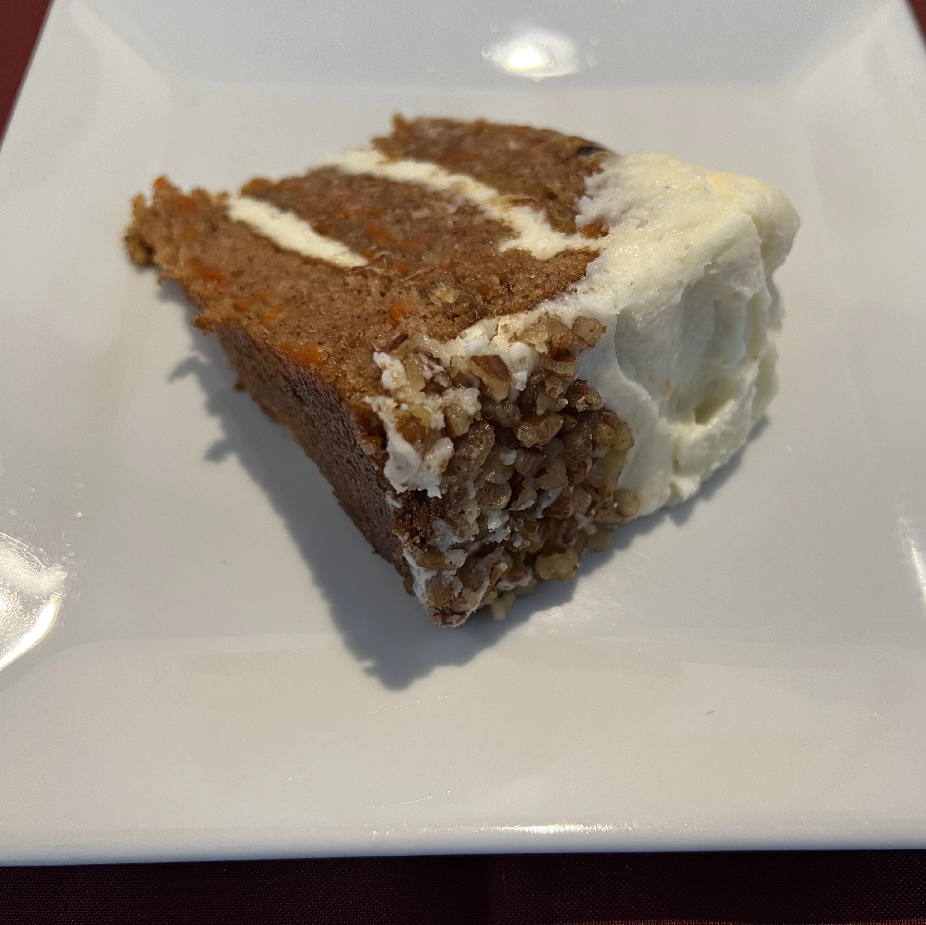 Delicious slice of carrot cake with cream cheese frosting on a plate.