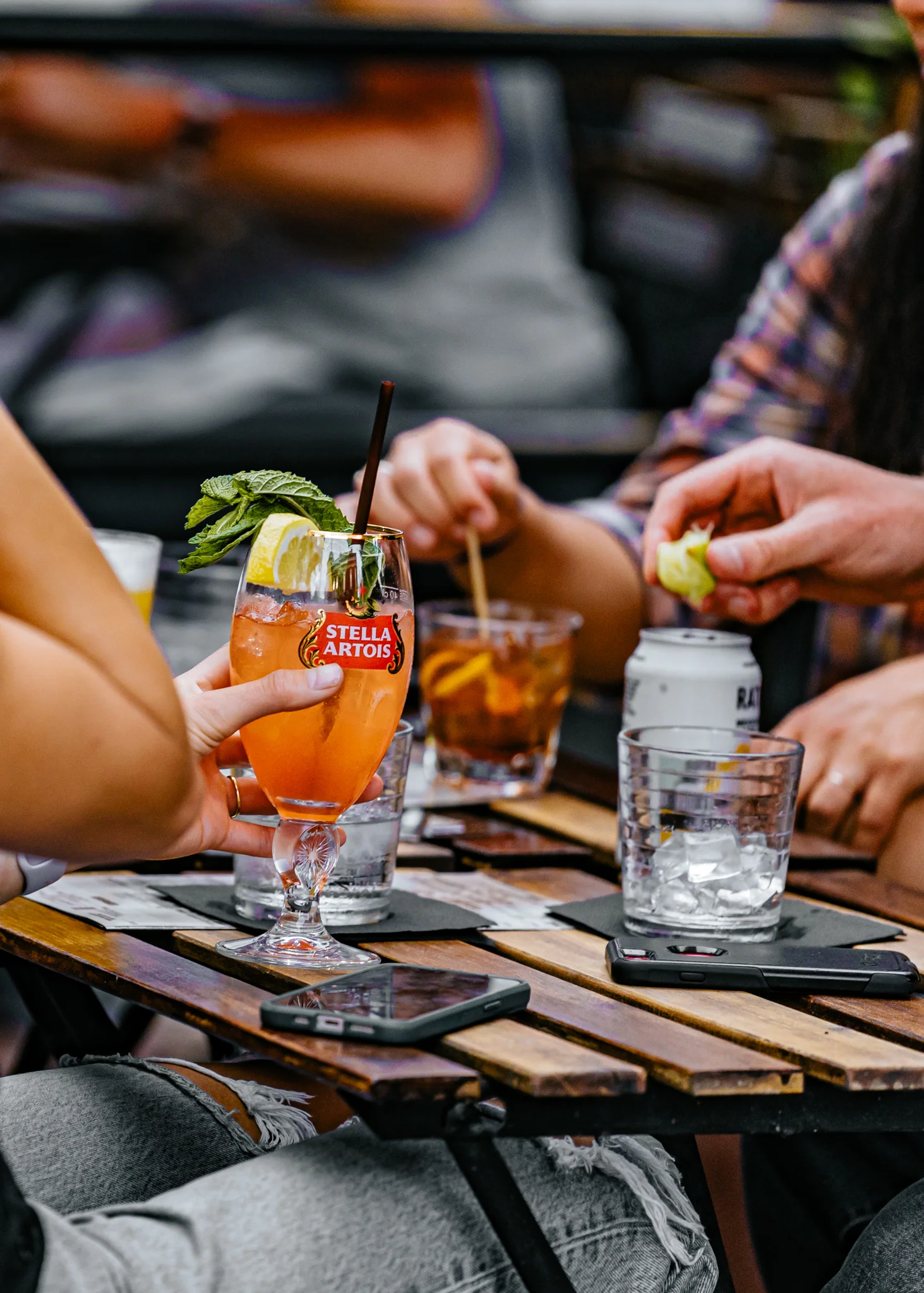 Colorful cocktails on a wooden table at a lively outdoor bar