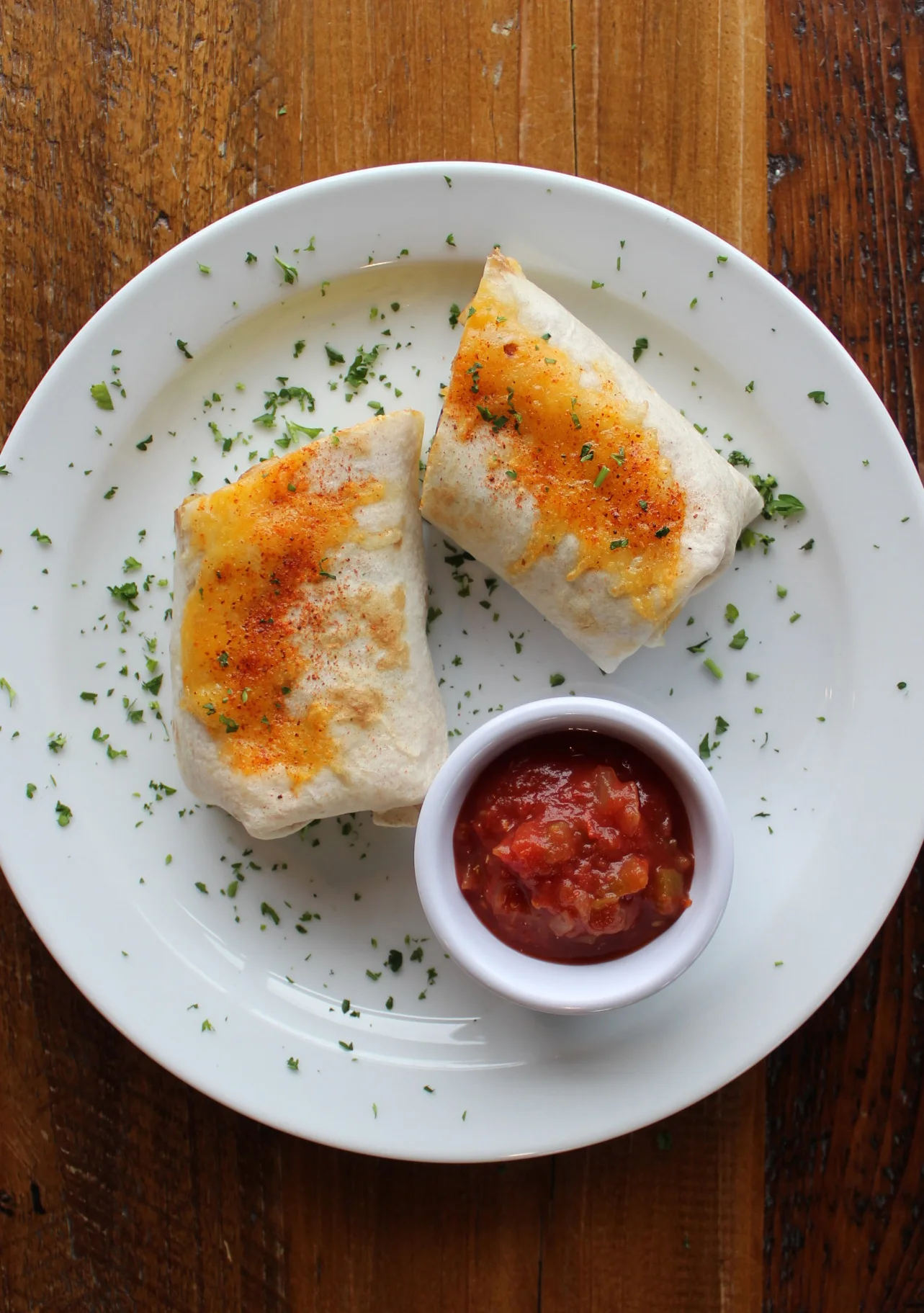 Cheesy burritos served with salsa in a rustic setting