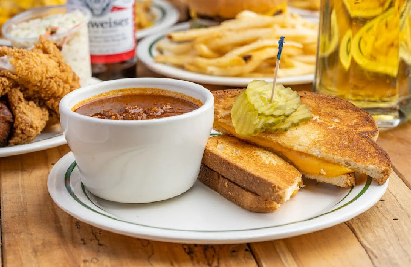Bowl of chili with grilled cheese sandwich and pickles