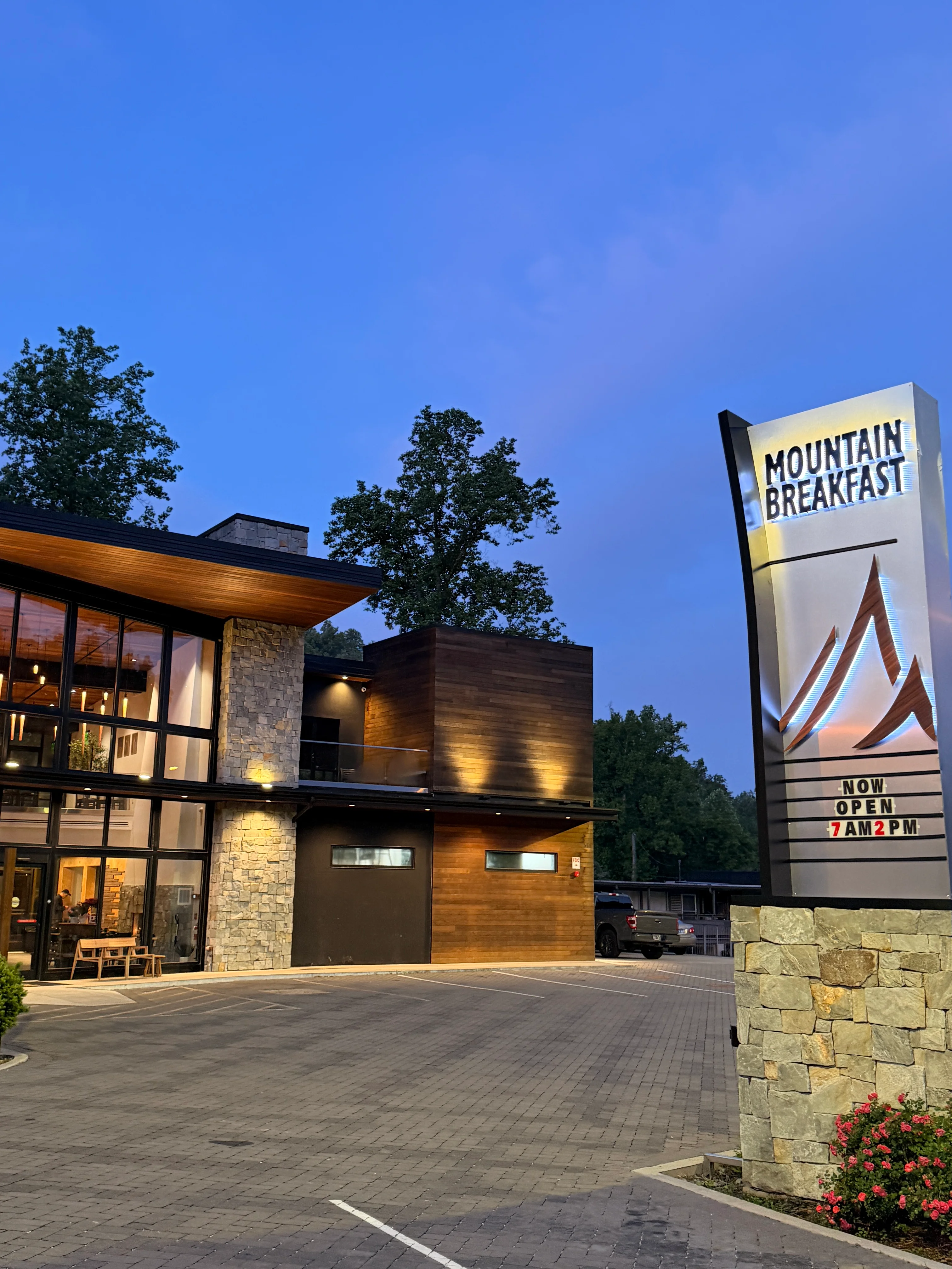 A modern building with large windows and a unique architectural design, featuring a combination of stone and wooden elements.
