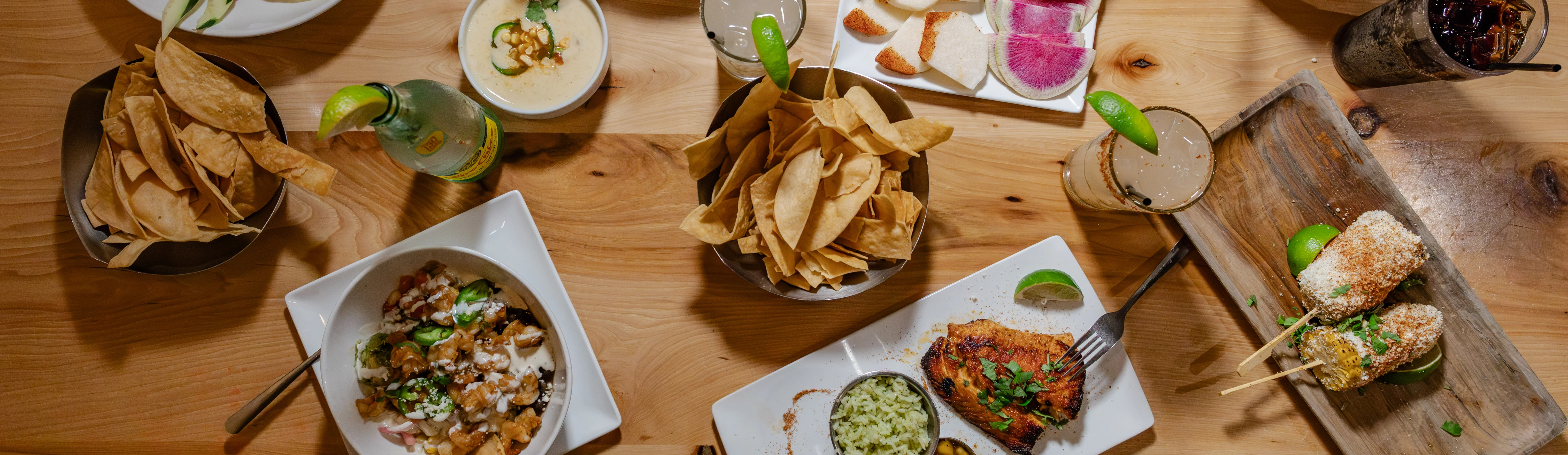 Colorful Mexican feast with tacos, elote, and fresh guacamole