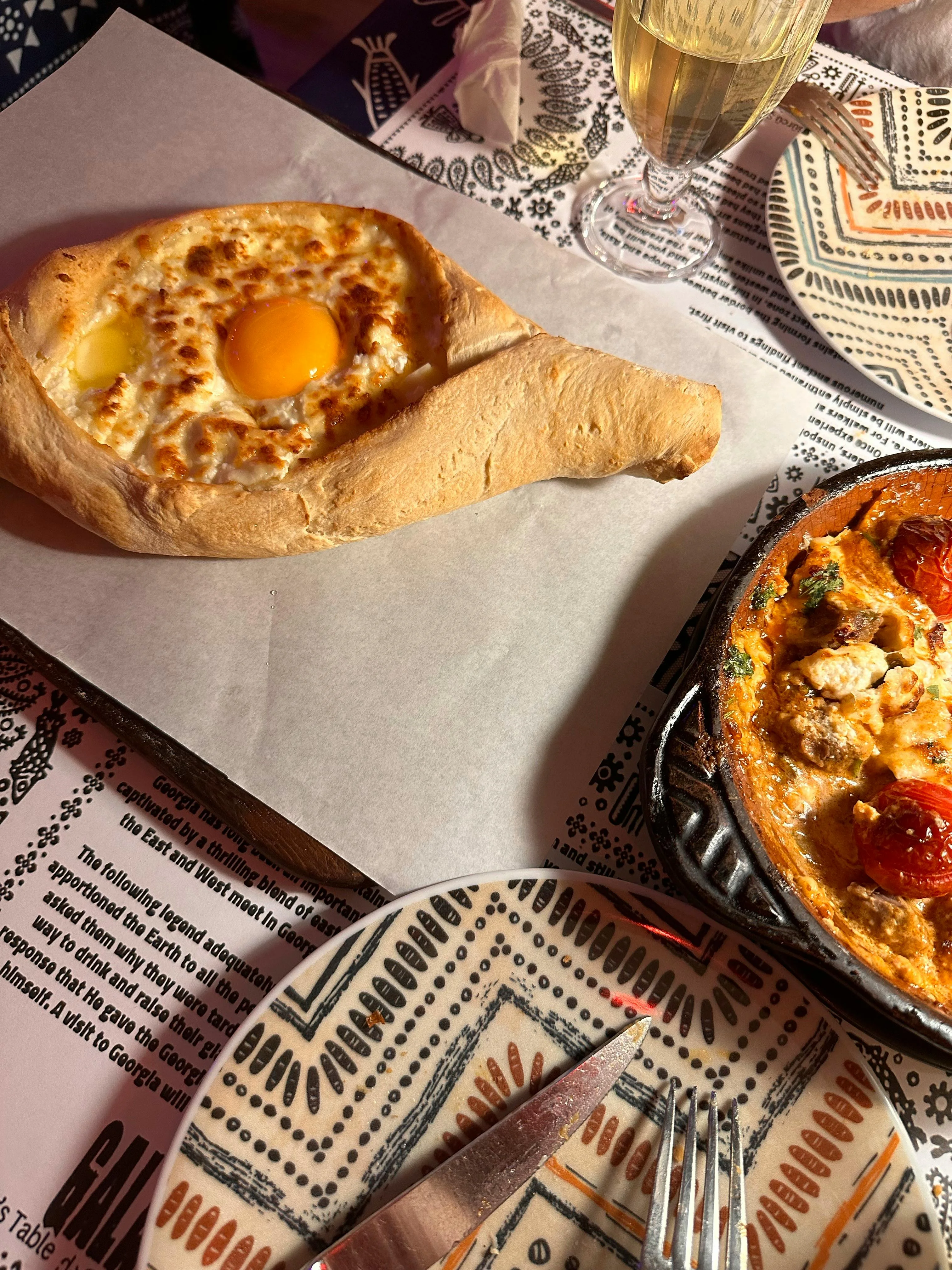Georgian Adjaruli Khachapuri with cheese and egg at restaurant table