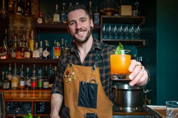 Bartender showcasing a vibrant cocktail at a stylish bar