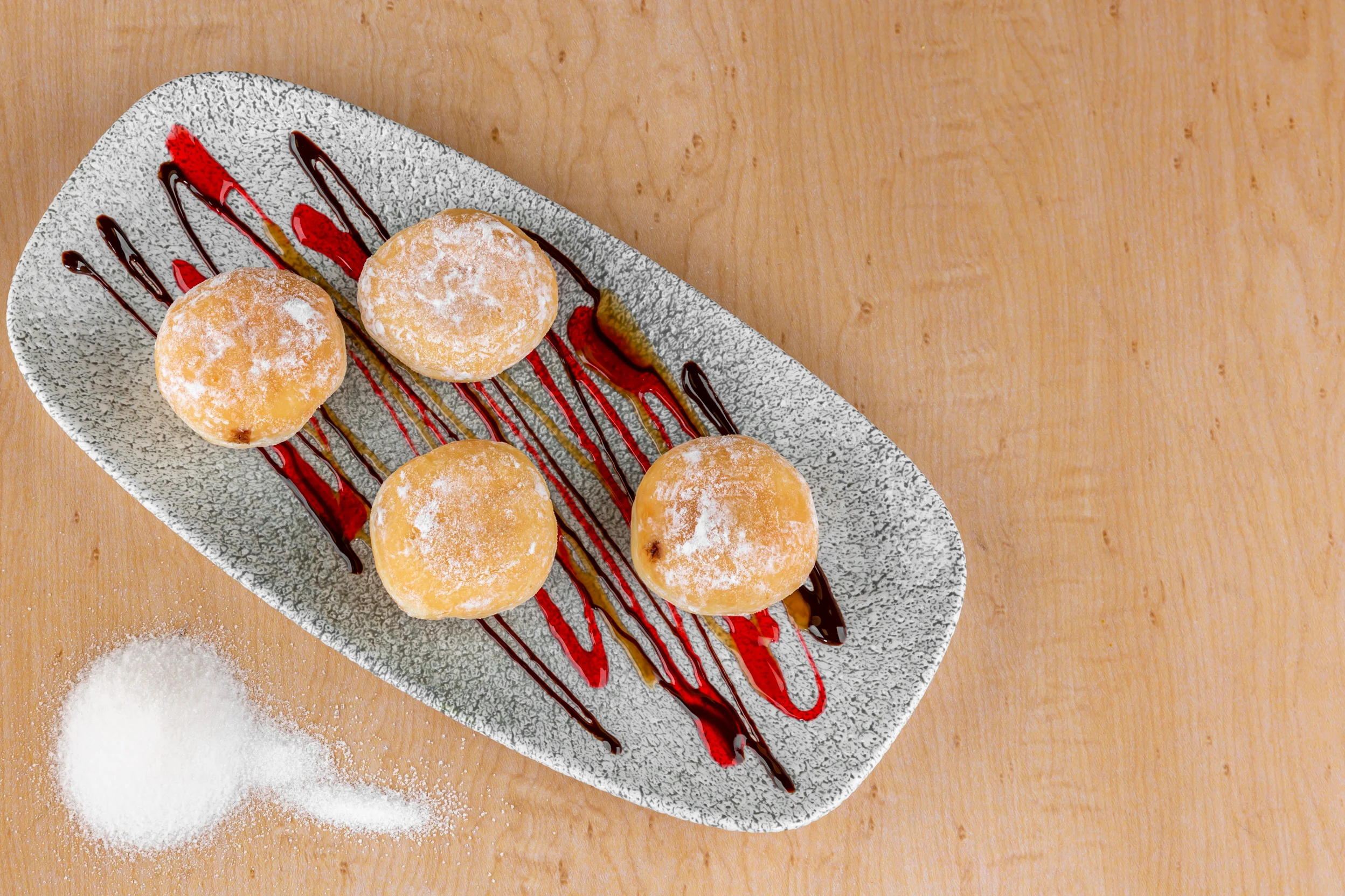 Delicious Italian zeppole dusted with powdered sugar and drizzled with sauce