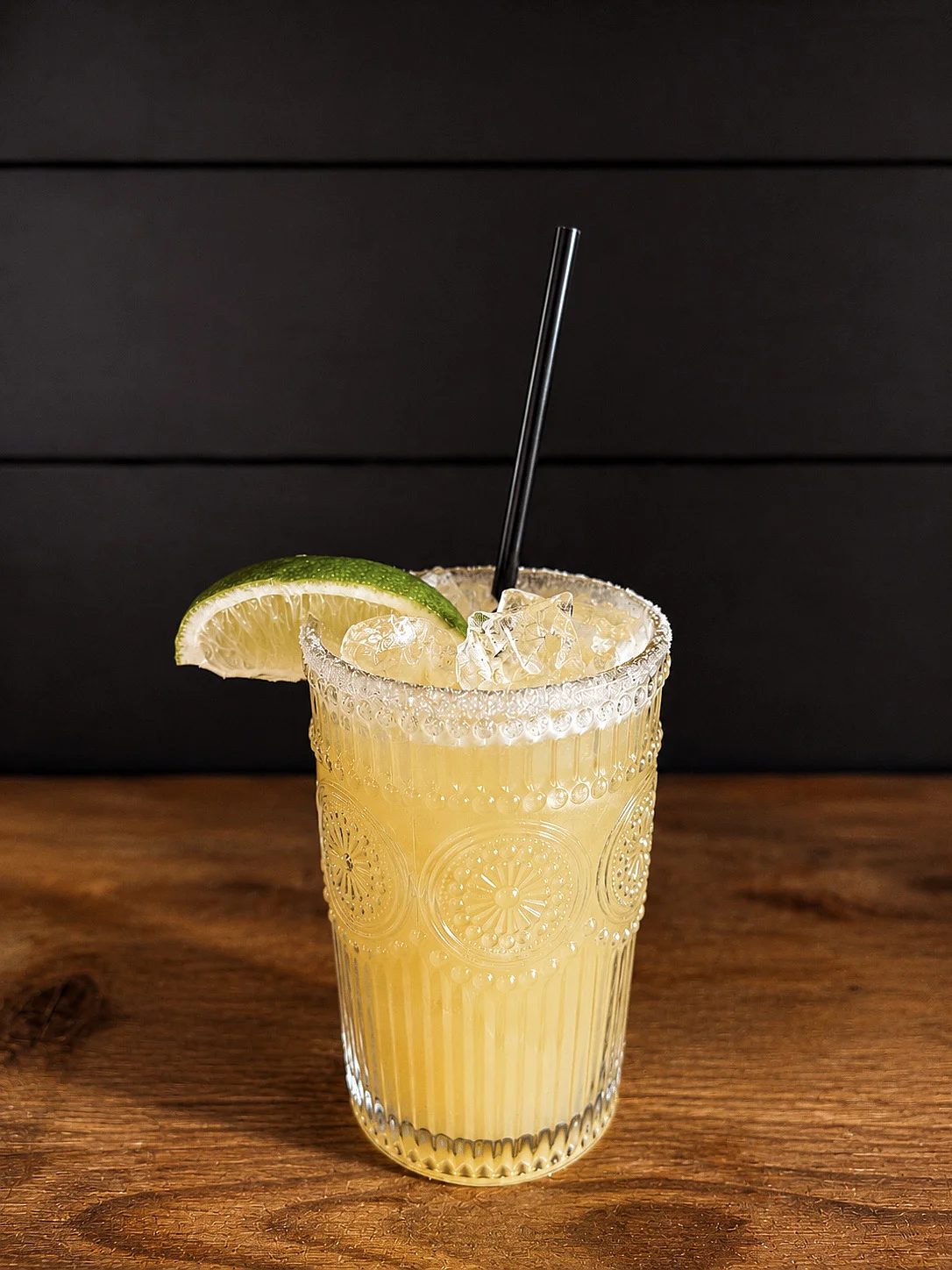 A refreshing cocktail with lime garnish in a decorative glass.