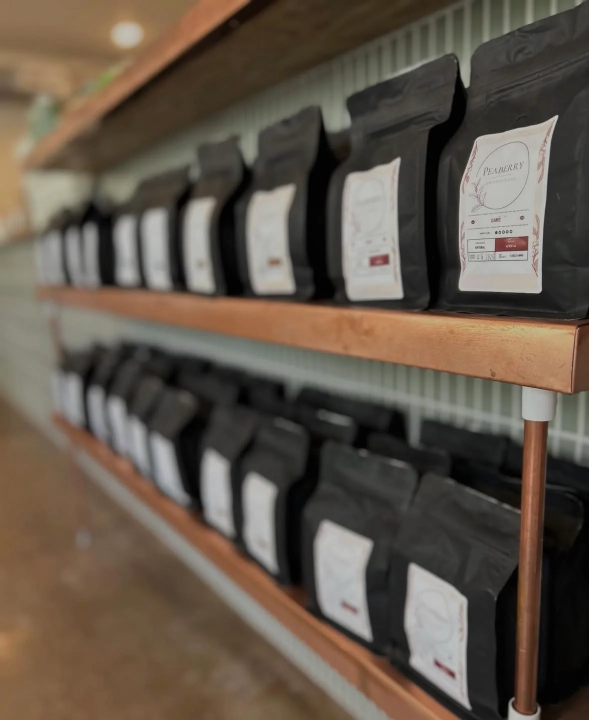 Display of coffee bags on wooden shelves in a cozy café
