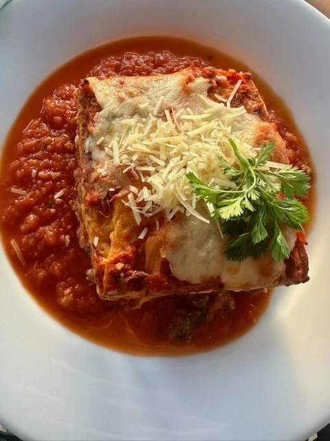 Lasagna served with marinara sauce and garnished with cheese and herbs.