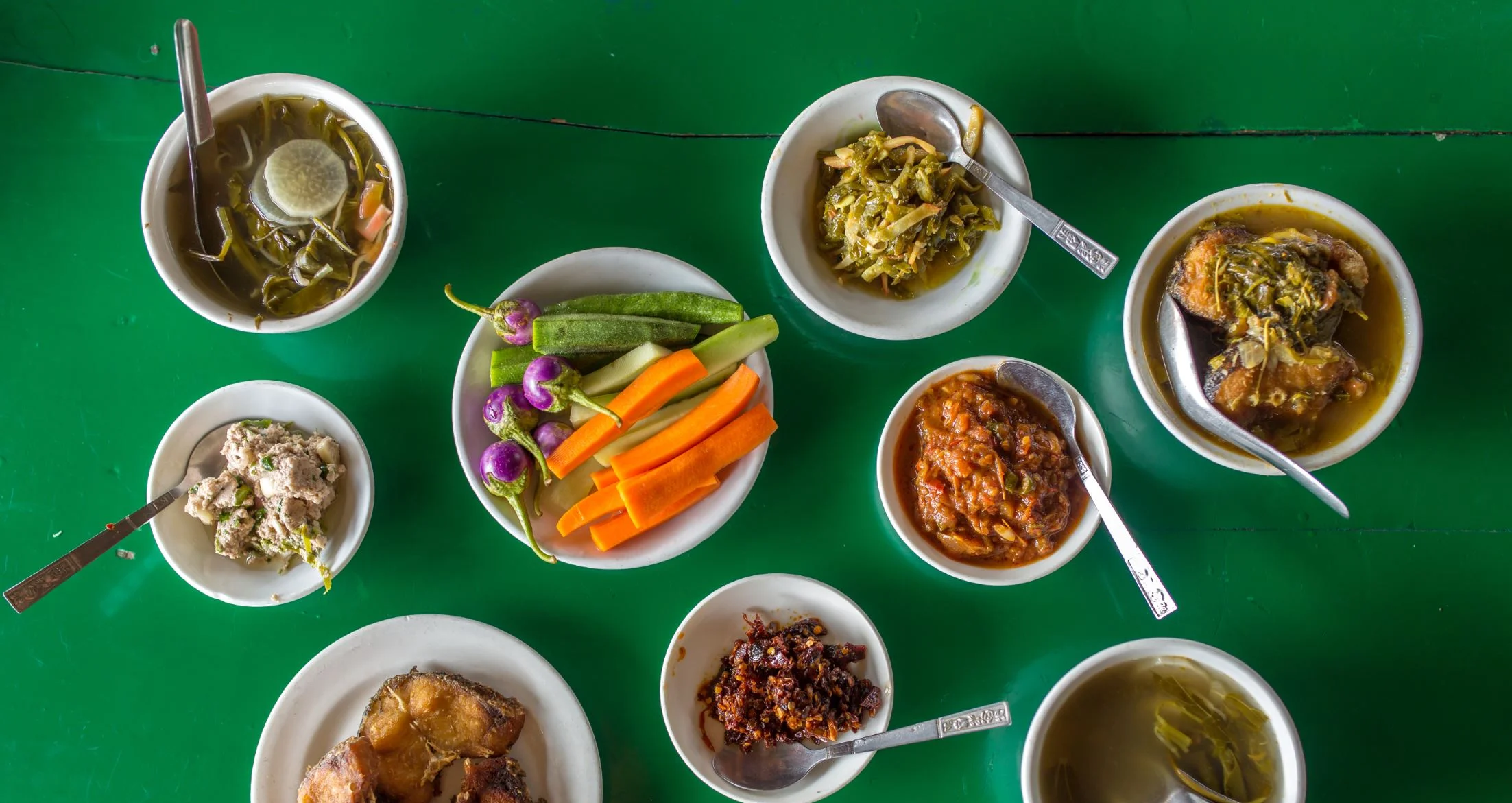 Traditional Burmese meal spread with curries, fried fish, vegetables, and dipping sauces