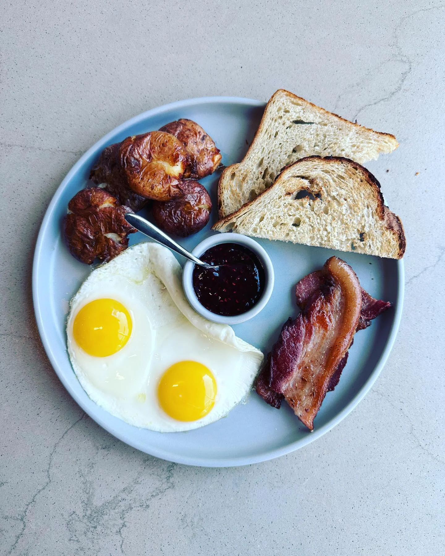 Classic breakfast plate with eggs, bacon, toast, and jam