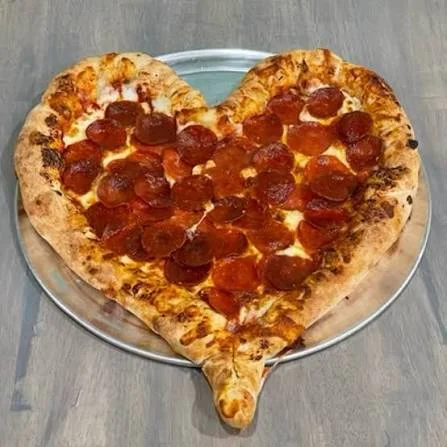 Heart-shaped pepperoni pizza on a silver platter
